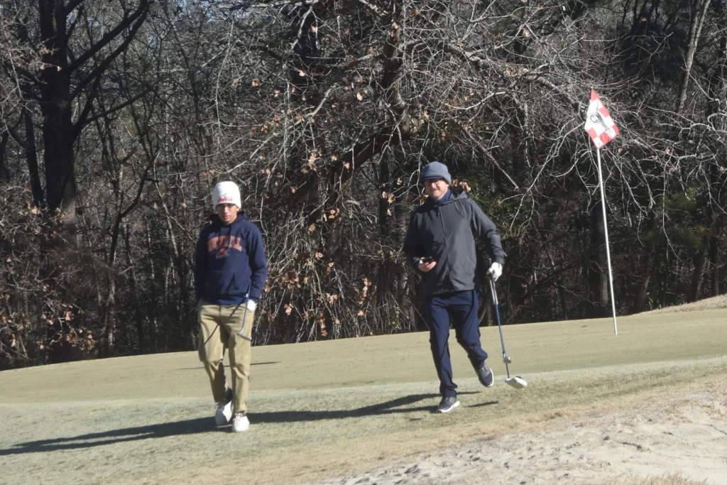 Mentor guiding a teen on the golf course, representing mentorship and goal setting.