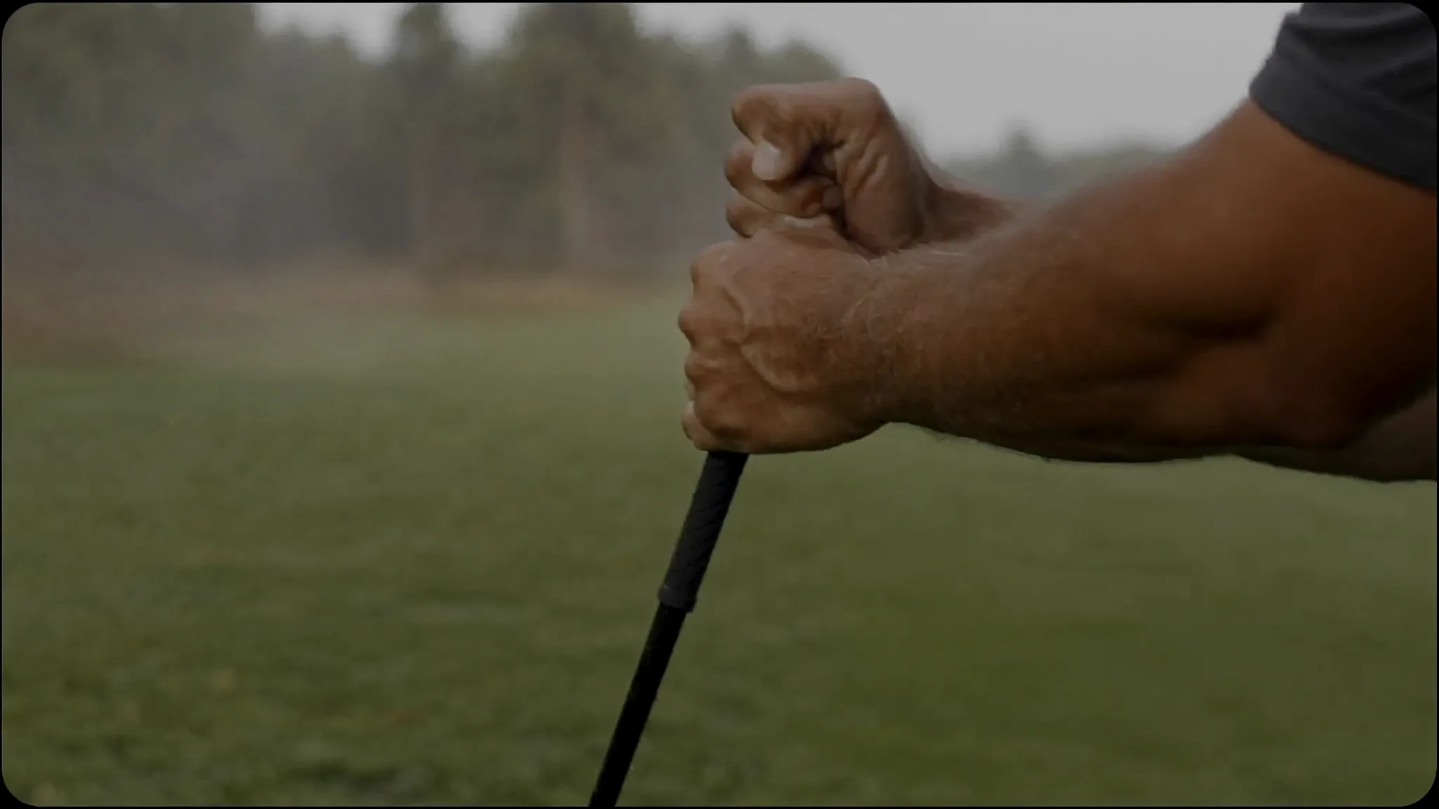 Mental grip: a man's hands gripping a golf club too tightly with white knuckles on a misty morning among longleaf pines